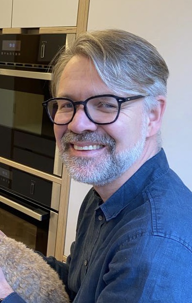 Peter Hegarty, a white man with grey hair and beard wearing black glasses.